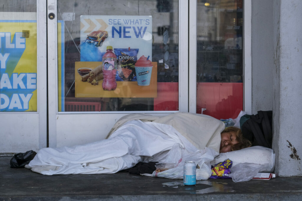 Homeless people sleep at an entrance of a 7-Eleven store at 8th street and Alvarado Avenue in Los Angeles, Aug. 16, 2022. (Photo by Ringo Chiu)