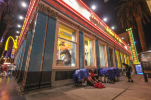 Homeless sit on the sidewalk outside Ripley's Believe It or Not! in Los Angeles, Aug. 17, 2022. (Photo by Ringo Chiu)