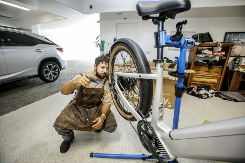 More and more businesses are offering to come to their customer's homes. Here Hitch Bekraoui builds a new electric bike  at a home in Manhattan Beach, CA recently in October,  2022. Photo by David Sprague